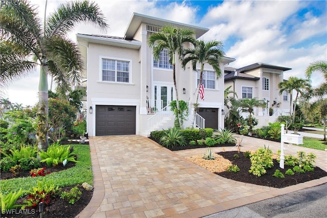 view of front facade with a standing seam roof, decorative driveway, a garage, and stucco siding