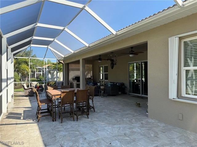 view of patio with glass enclosure, outdoor dining area, and a ceiling fan