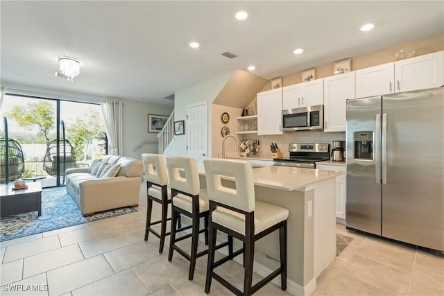14127 Oviedo Pl, Fort Myers, FL 33905 - kitchen with a breakfast bar, stainless steel appliances, light countertops, decorative backsplash, and a kitchen island with sink