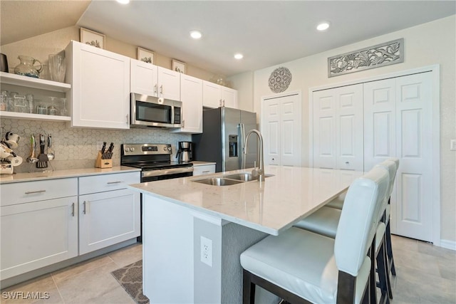 14127 Oviedo Pl, Fort Myers, FL 33905 - kitchen with an island with sink, a kitchen bar, appliances with stainless steel finishes, and backsplash