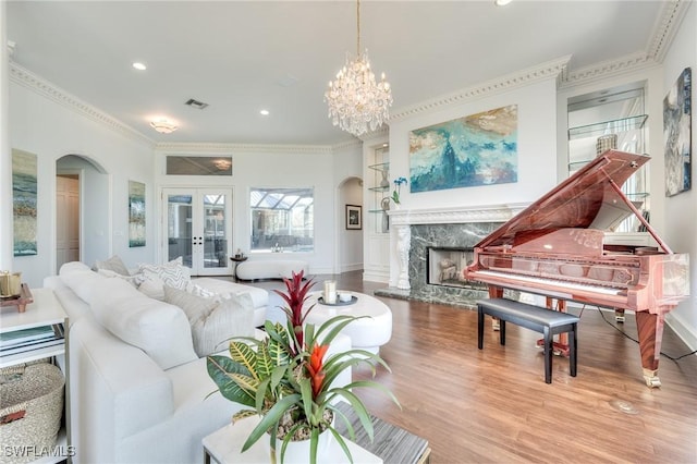 living area featuring arched walkways, crown molding, a fireplace, visible vents, and wood finished floors