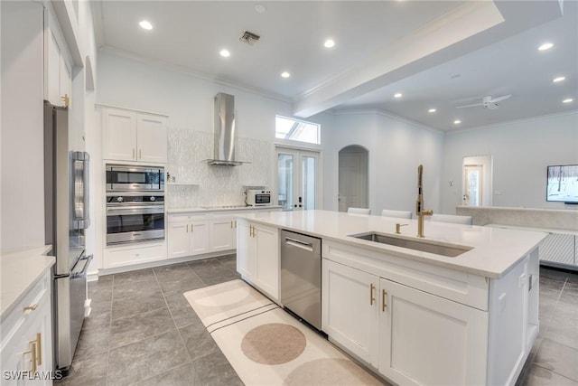 kitchen featuring visible vents, arched walkways, appliances with stainless steel finishes, wall chimney range hood, and a sink