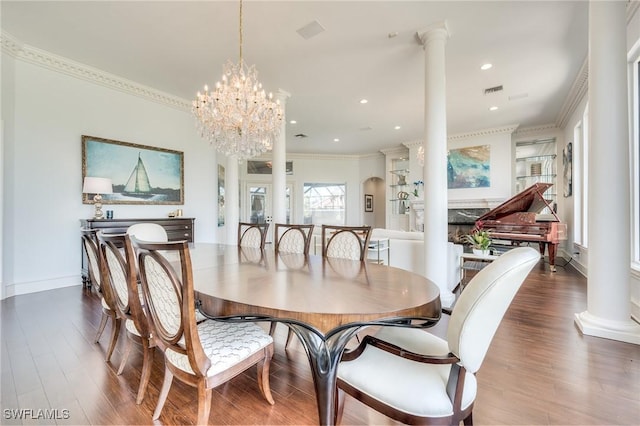 dining area with an inviting chandelier, decorative columns, ornamental molding, and wood finished floors