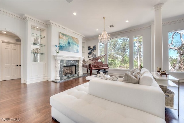 living room with built in shelves, dark wood-style flooring, a healthy amount of sunlight, and a fireplace