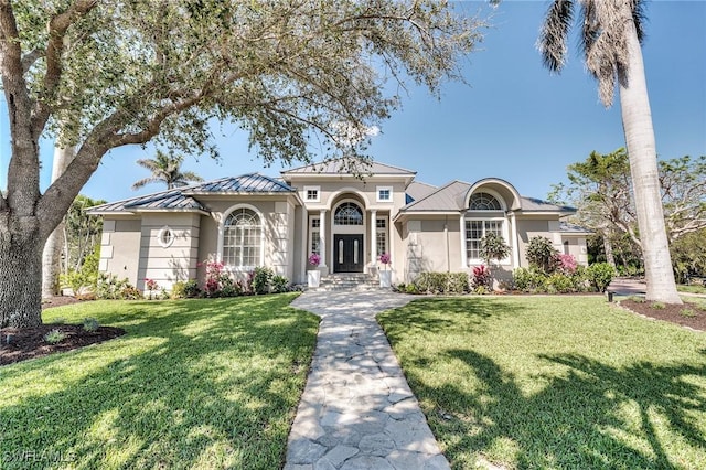 mediterranean / spanish-style home with a standing seam roof, stucco siding, metal roof, and a front yard