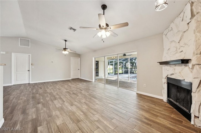 unfurnished living room featuring visible vents, a high end fireplace, ceiling fan, vaulted ceiling, and wood finished floors