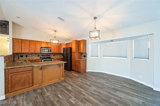 kitchen featuring stainless steel appliances, a peninsula, a sink, visible vents, and decorative backsplash