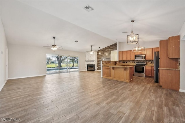 kitchen featuring a large fireplace, a breakfast bar, visible vents, open floor plan, and appliances with stainless steel finishes