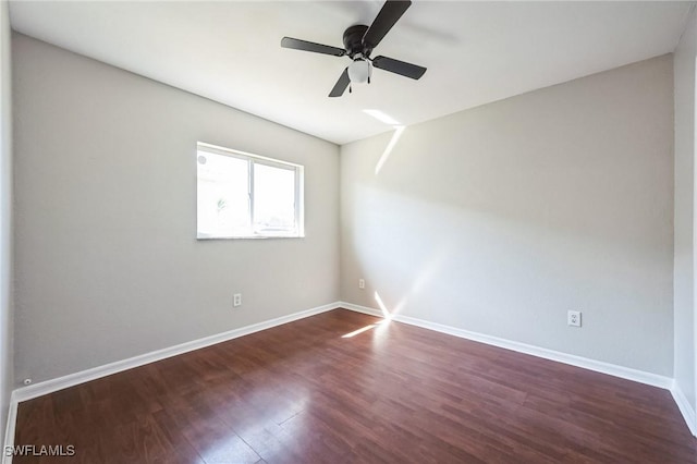 spare room with wood finished floors, a ceiling fan, and baseboards