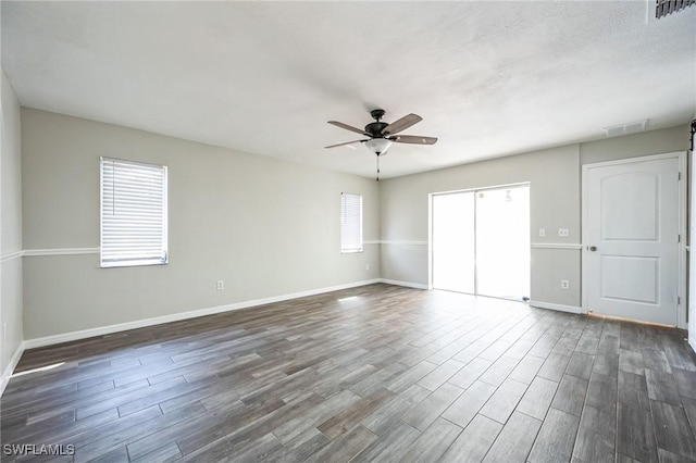 spare room with visible vents, dark wood finished floors, and a ceiling fan