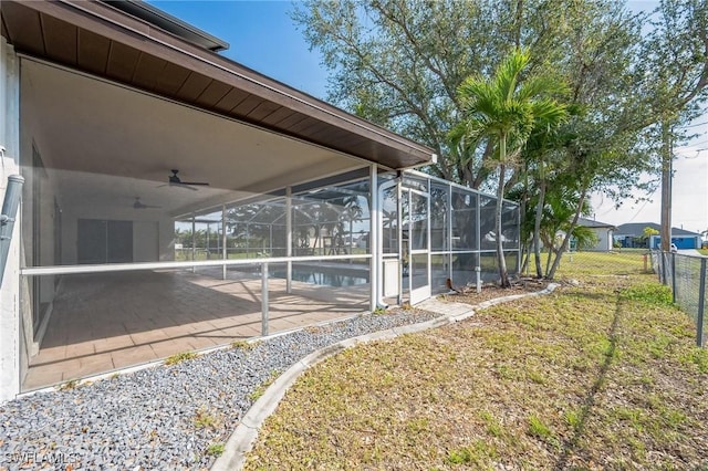 view of yard featuring an outdoor pool, a patio, glass enclosure, ceiling fan, and fence