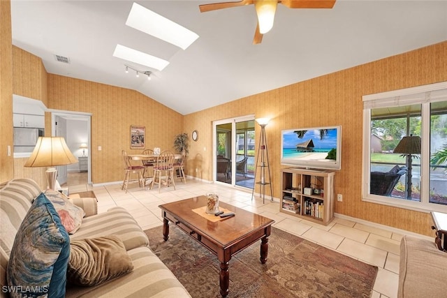 living area with vaulted ceiling with skylight, light tile patterned flooring, visible vents, and wallpapered walls