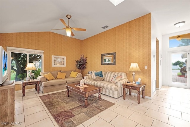 living area with light tile patterned floors, ceiling fan, vaulted ceiling, baseboards, and wallpapered walls