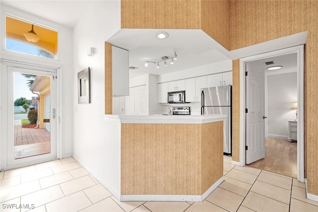 kitchen featuring light tile patterned floors, visible vents, appliances with stainless steel finishes, white cabinets, and a peninsula