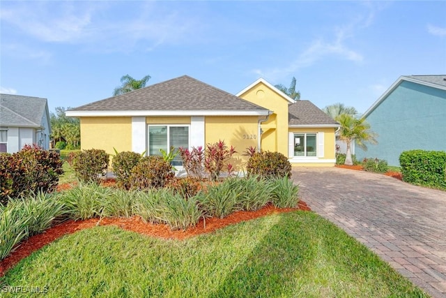 view of front of property with decorative driveway, roof with shingles, and stucco siding