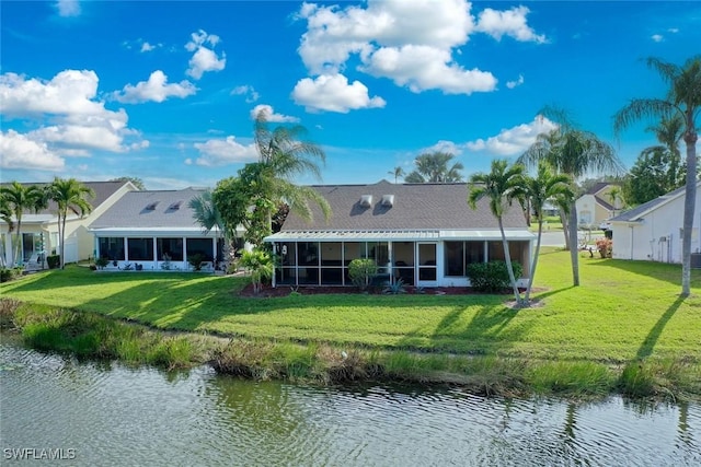 rear view of property featuring a sunroom, a water view, and a lawn