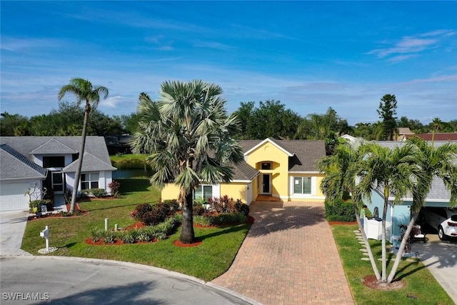 view of front facade featuring stucco siding, decorative driveway, and a front yard