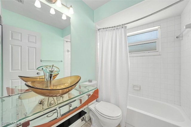 bathroom with shower / bath combo, a sink, and toilet