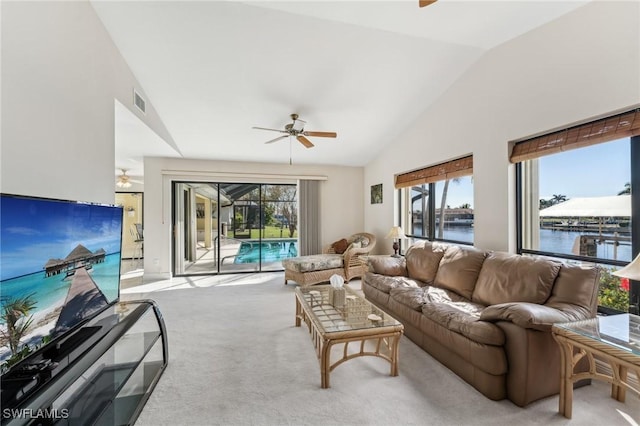 carpeted living room with a water view, a sunroom, a ceiling fan, and a wealth of natural light