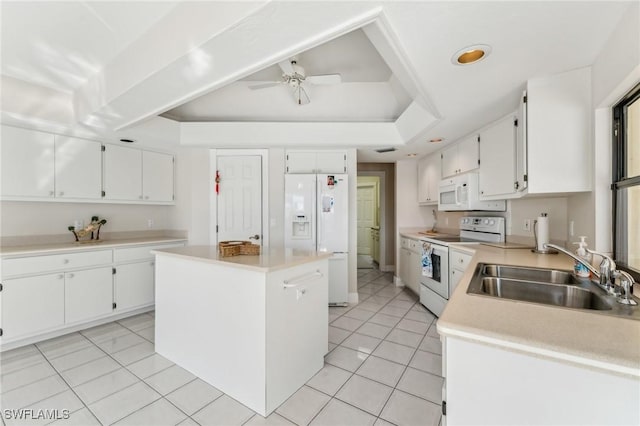 kitchen featuring white appliances, a sink, white cabinets, a center island, and a raised ceiling