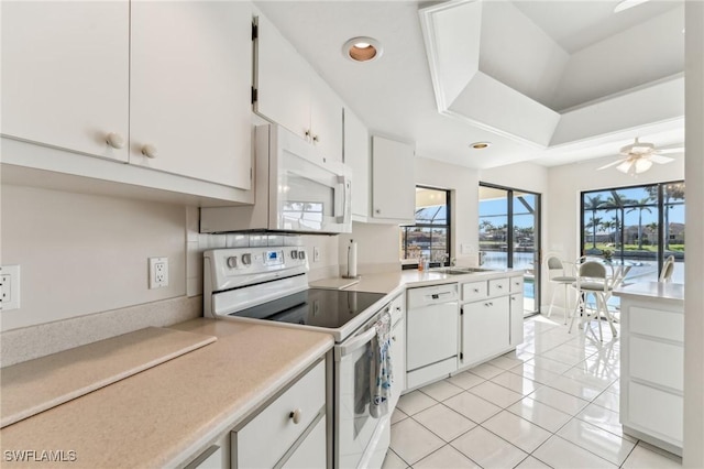 kitchen featuring white appliances, light tile patterned floors, ceiling fan, light countertops, and white cabinetry