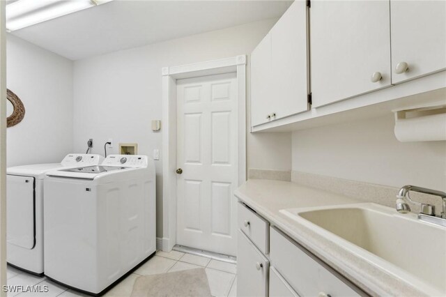 washroom with light tile patterned floors, cabinet space, a sink, and washing machine and clothes dryer