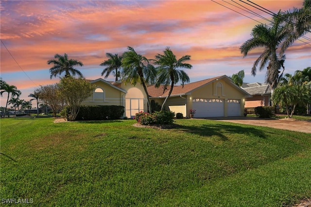 ranch-style home featuring driveway, a garage, a front lawn, and stucco siding