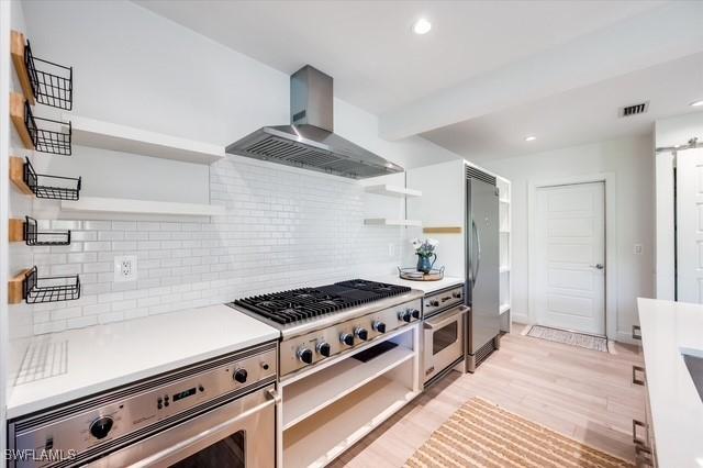 kitchen featuring stainless steel appliances, visible vents, wall chimney range hood, and open shelves