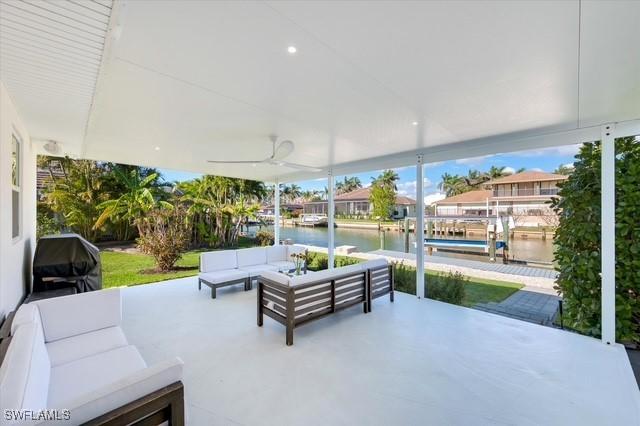 view of patio with outdoor lounge area, a water view, grilling area, a ceiling fan, and a dock