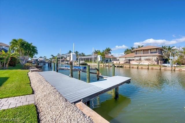 view of dock featuring a water view, boat lift, and a lawn