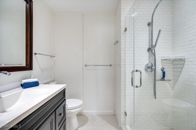 bathroom with toilet, a stall shower, tile patterned floors, and vanity