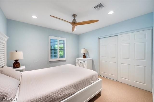 bedroom with a closet, recessed lighting, visible vents, and light colored carpet