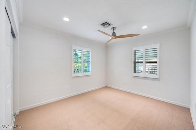 empty room featuring plenty of natural light, visible vents, ceiling fan, and crown molding