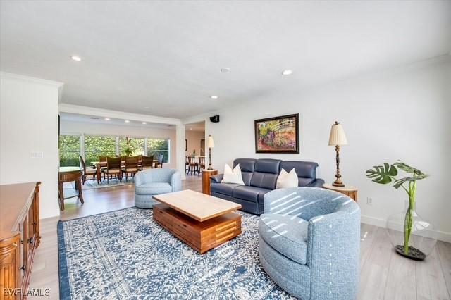 living area featuring light wood-style flooring, baseboards, crown molding, and recessed lighting