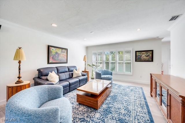 living area featuring light wood-style floors, recessed lighting, visible vents, and baseboards