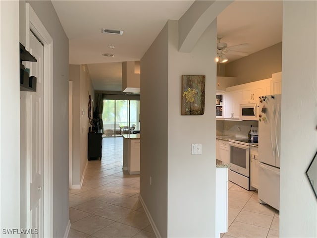 hallway with light tile patterned floors, visible vents, and baseboards