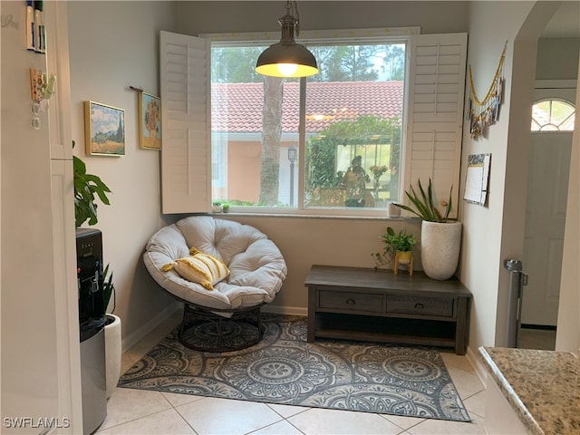 sitting room featuring baseboards, arched walkways, and tile patterned floors