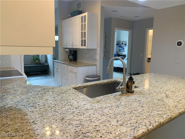 kitchen with light stone counters, white cabinets, and a sink