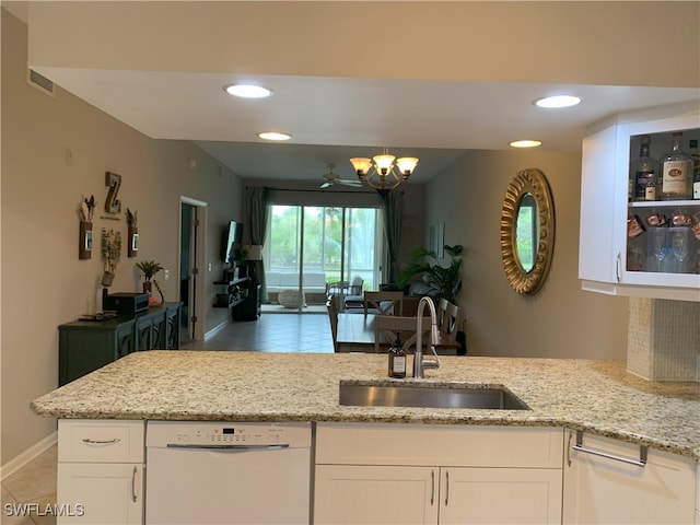 kitchen with light stone counters, open floor plan, white cabinets, a sink, and dishwasher