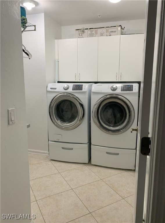 clothes washing area featuring washing machine and dryer, cabinet space, and light tile patterned floors