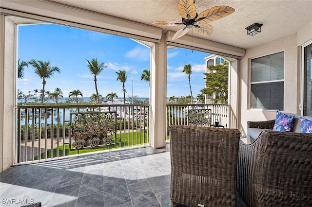 view of patio featuring a water view, a balcony, and a ceiling fan