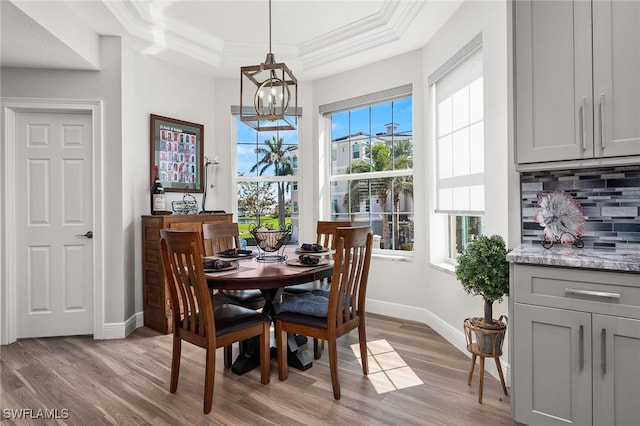 dining area featuring a raised ceiling, crown molding, and wood finished floors