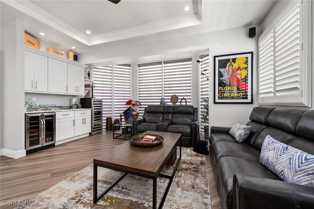 living room with beverage cooler, a bar, wood finished floors, and a raised ceiling