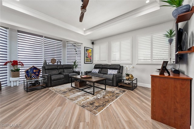 living area with a tray ceiling, wood finished floors, and crown molding