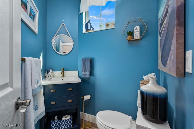 bathroom with baseboards, vanity, and toilet