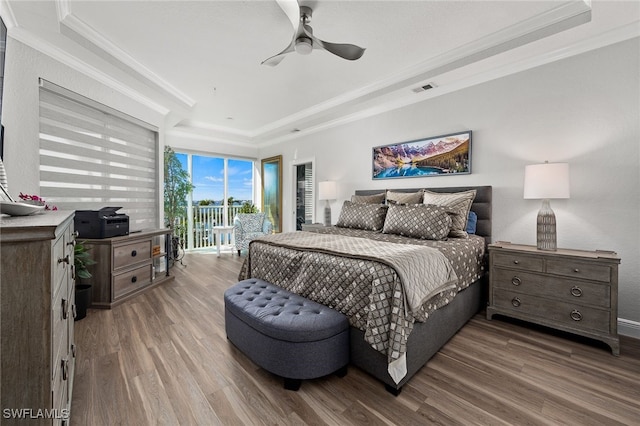 bedroom featuring crown molding, a raised ceiling, visible vents, wood finished floors, and access to outside