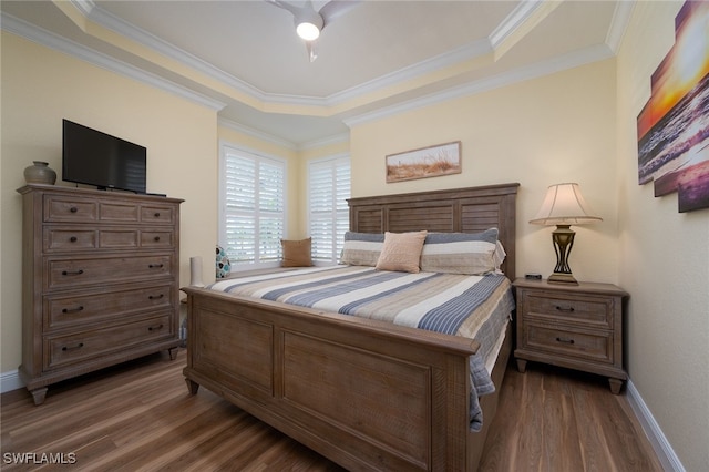 bedroom with wood finished floors, a ceiling fan, baseboards, a raised ceiling, and crown molding