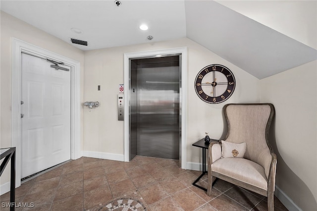 interior space featuring baseboards, vaulted ceiling, visible vents, and elevator