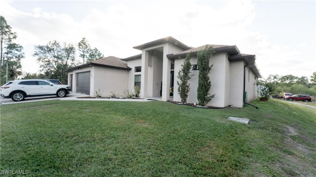 prairie-style house with a garage, driveway, a front lawn, and stucco siding