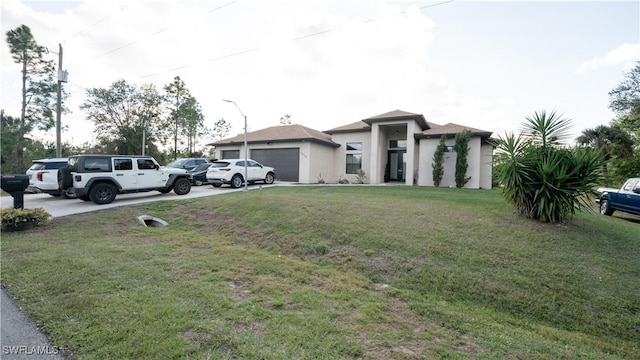 prairie-style house featuring a garage, driveway, a front lawn, and stucco siding